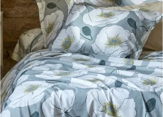 Parure de lit aux grandes fleurs blanches sur fond bleu dans une chambre chaleureuse