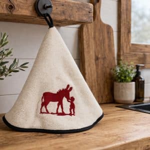 Essuie-mains beige brodé d’un motif rouge accroché dans une cuisine en bois